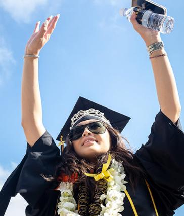 Graduate raises her arms in air