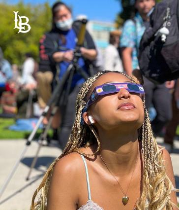 Student gazes up at the sun wearing eclipse glasses