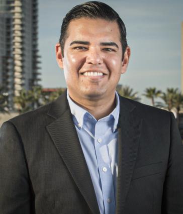 Man in a suit jacket poses in front of cityscape