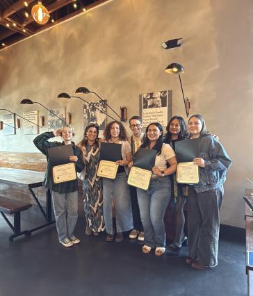 group of people standing in front of wall holding award certificates.