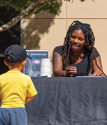 A student talks to a young child at a booth