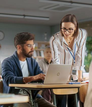 Woman teaching male student with laptop
