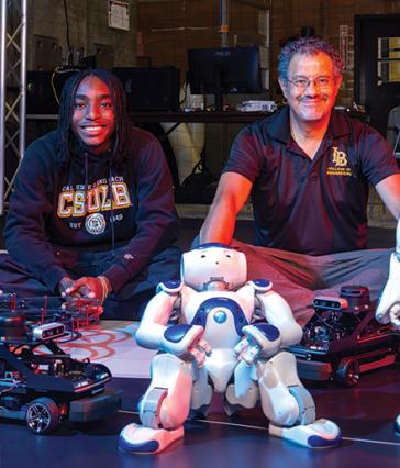 Two people sit side by side with a robot in a the foreground