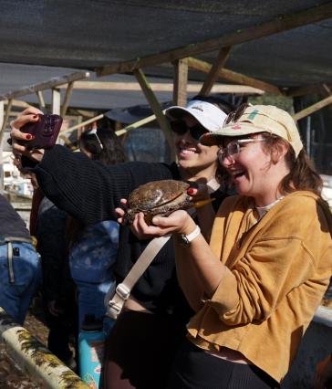 two people holding an abalone and taking a photo