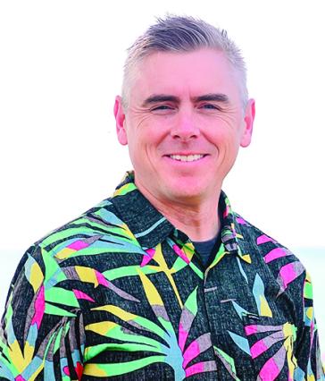 Man stands in front of white background in colorful shirt