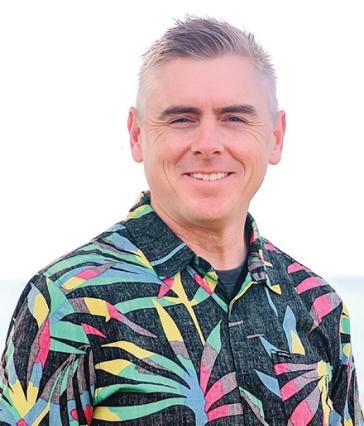 Man stands in front of white background in colorful shirt