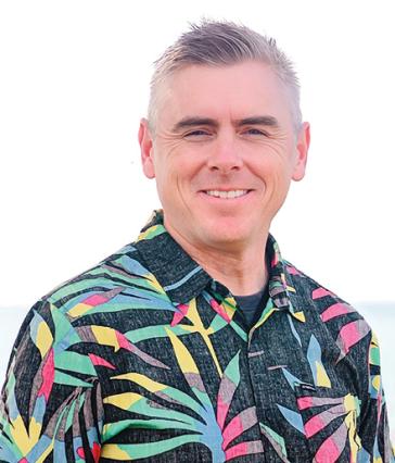 Man stands in front of white background in colorful shirt
