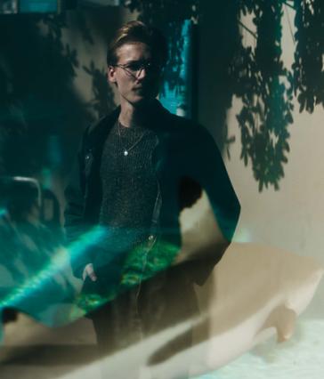 A CSULB student researcher reflected in a shark tank's glass