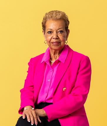 Person wearing pink faces camera with yellow background