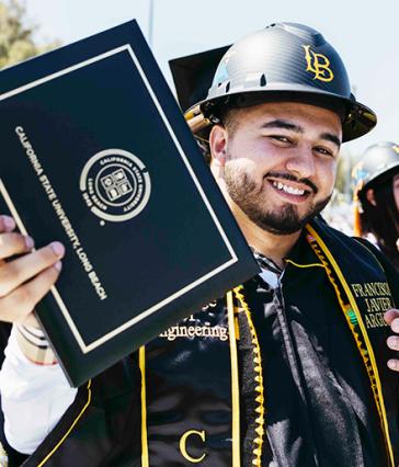 CSULB graduate with hard hat holding his diploma