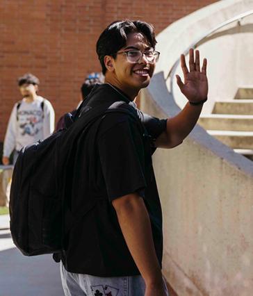 Student waving in front of stairs