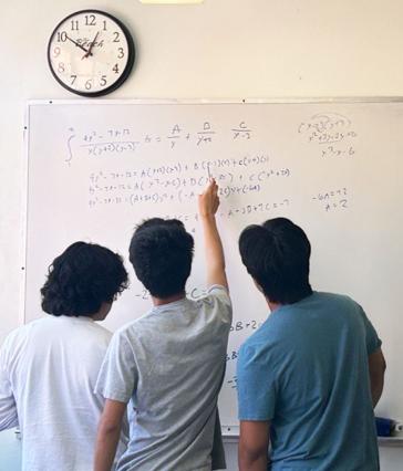 Math students work on a problem on the whiteboard