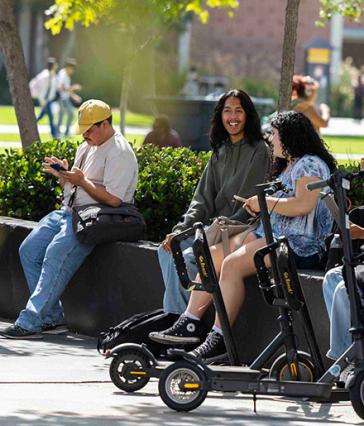 Students sitting and chatting, scooters in front of them