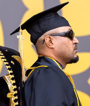 A graduate wearing regalia, with a sombrero draped over his back