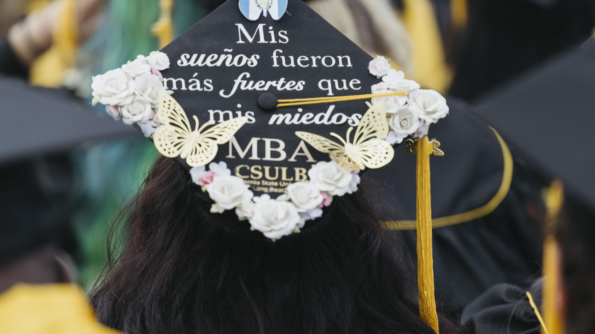 Graduation cap reading "Mis sueños fueron más fuertes que mis miedos" with butterfly and flower decorations
