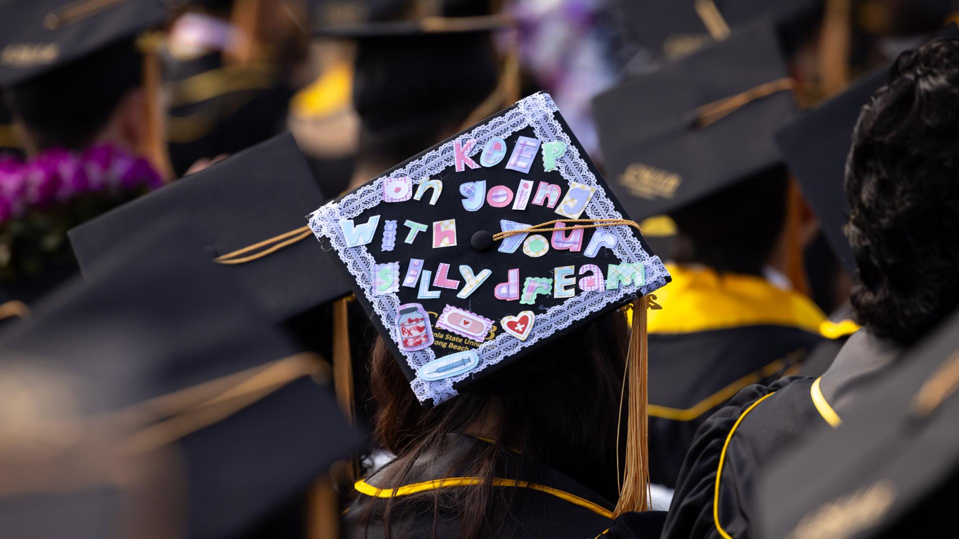 Graduation cap reading "Keep going with your silly dreams" with colorful lettering