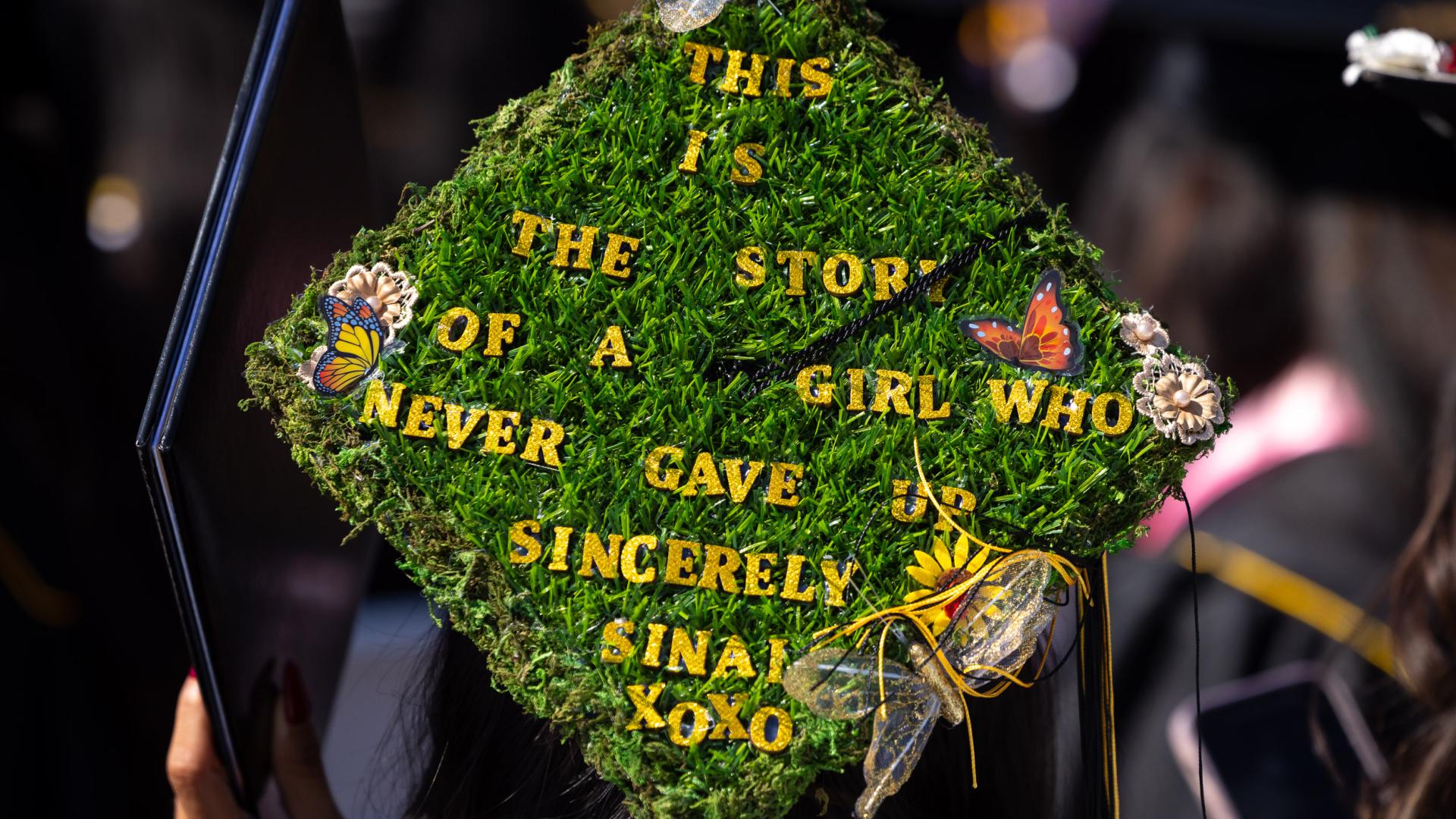 Graduation cap covered in moss reading "This is the story of a girl who never gave up — Sinai"