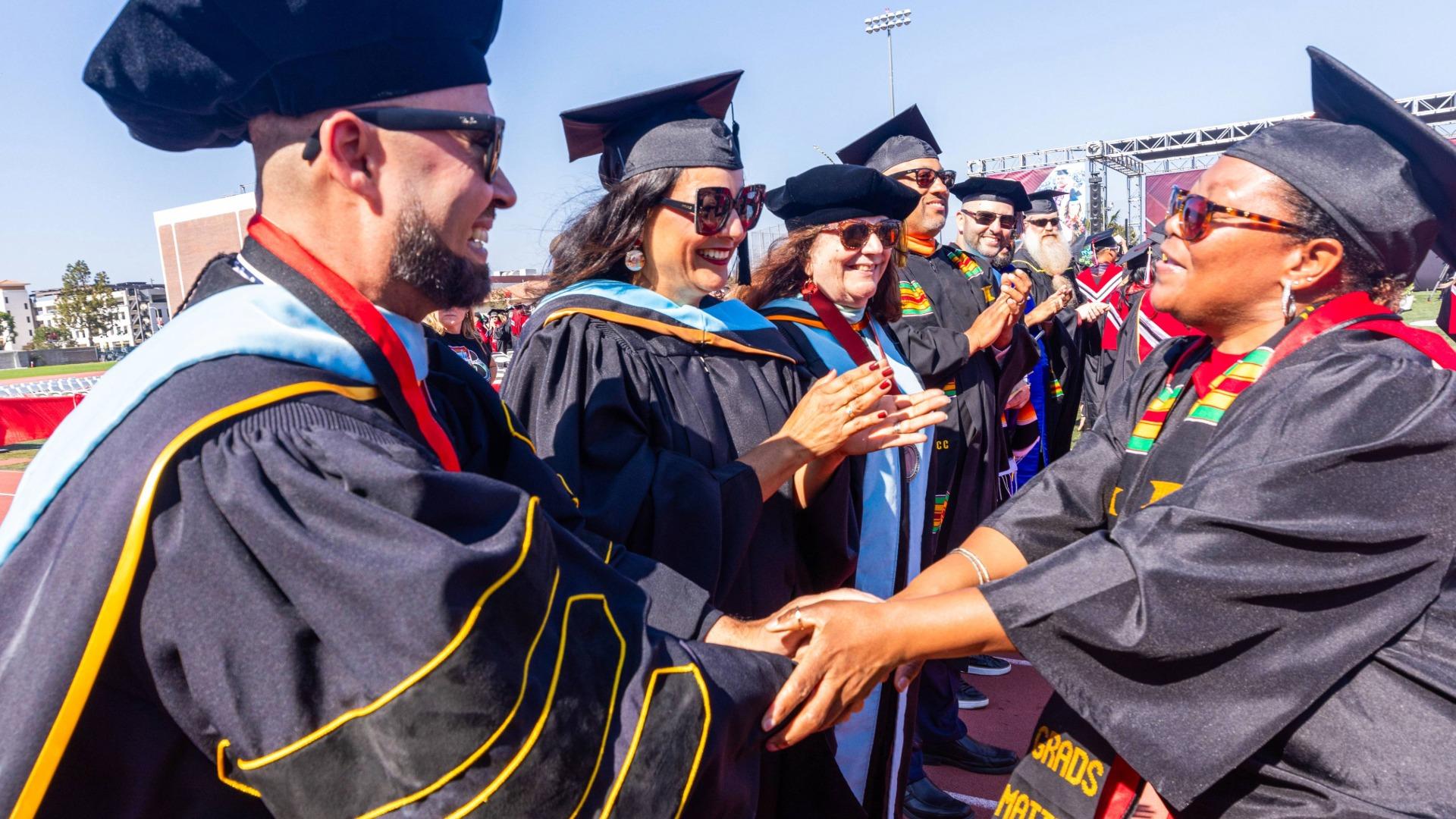 Mike Muñoz, left, congratulates graduates at Long Beach City College