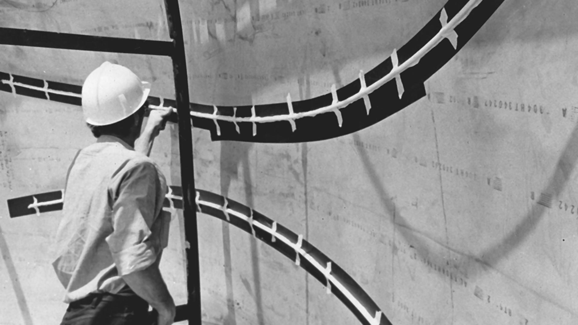 A workman works on a piece of Now
