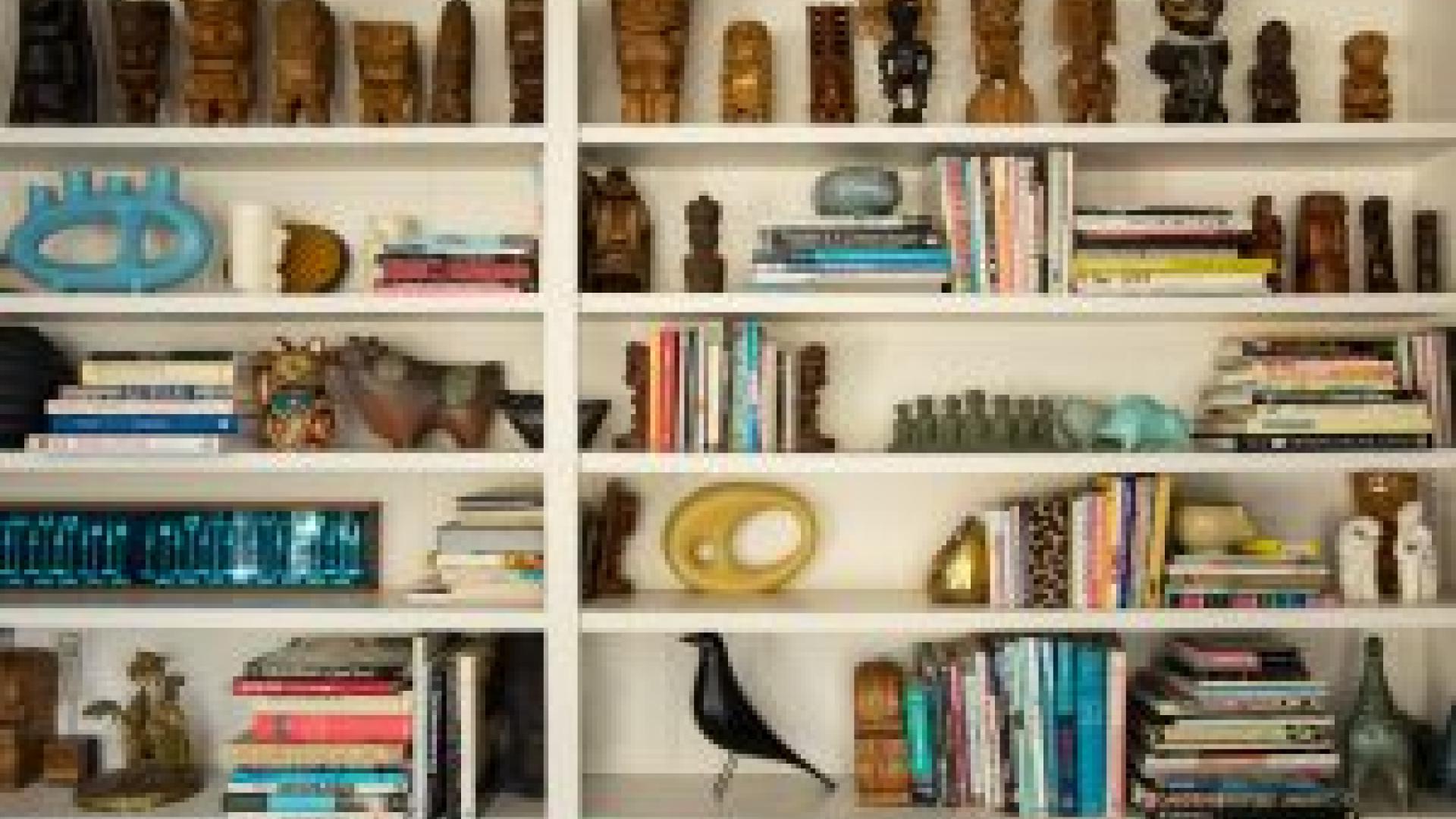 Bookshelf containing books and tiki collection