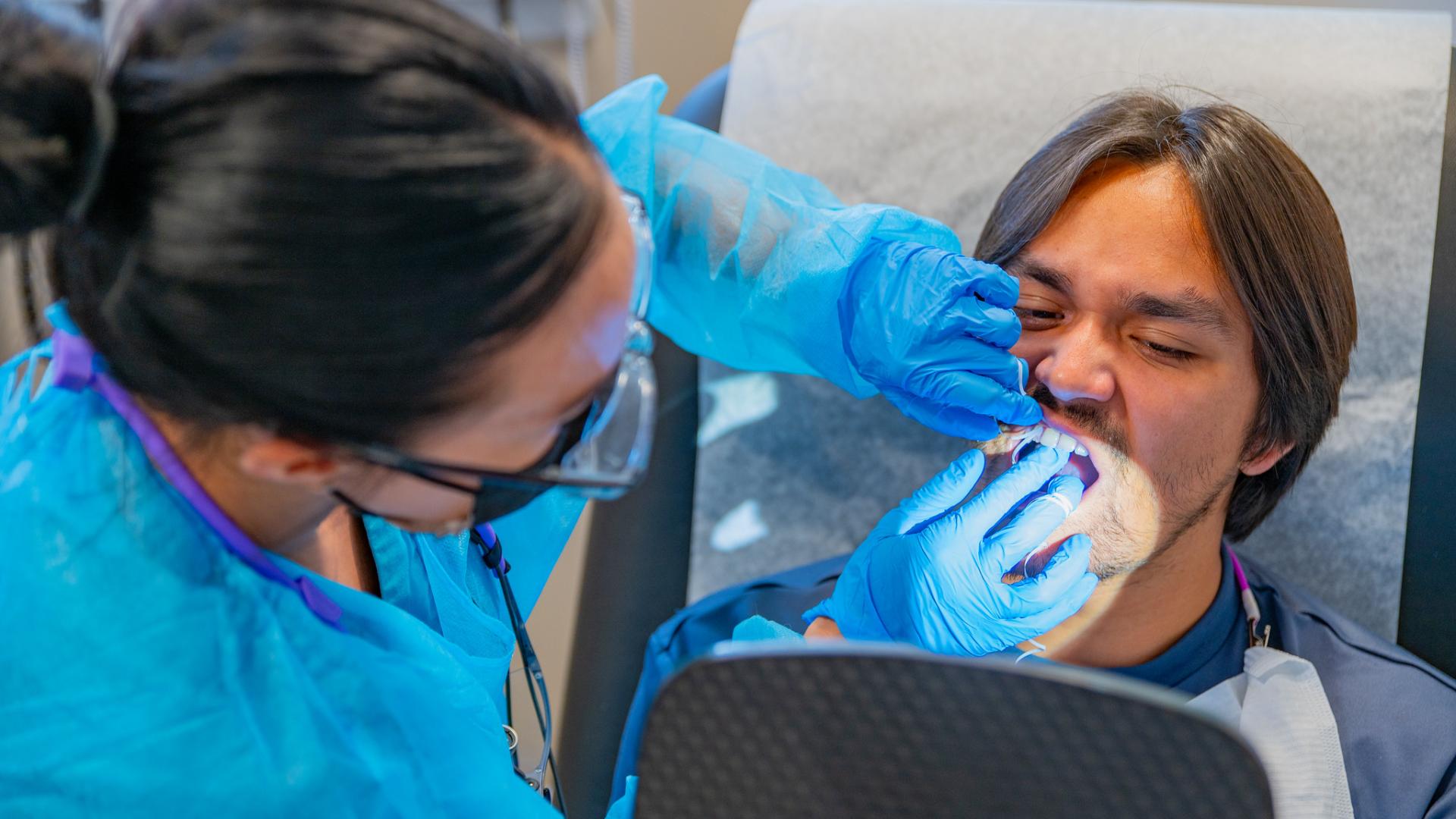 Student getting his teeth checked by a dentist.