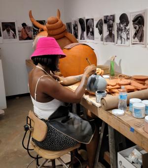 South African artist Zizipho Poswa working during her July 2023 residency at the CCC Zizipho Poswa, a black woman in a pink hat, works in profile towards the camera
