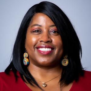 A person wearing spiral earrings smiles in a close-up portrait