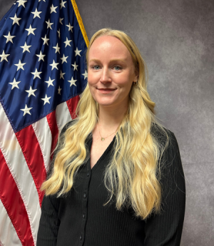Allyson Joy headshot in front of American flag.