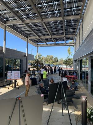 People standing under solar panels and looking at posters