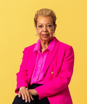 Person wearing pink faces camera with yellow background