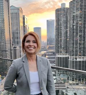 HDEV Dept Chair Kim Kelly smiling in front of a city skyline