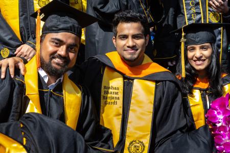 Students in Commencement garb pose for photo