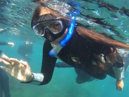 student waving underwater while snorkeling