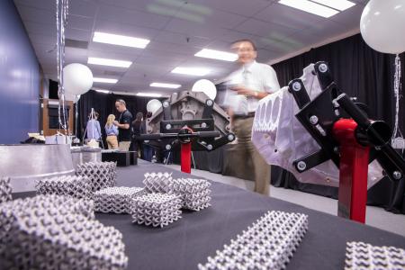 A display table showcases 3D-printed metal lattice structures and mechanical parts, while people converse in the background at the opening of the Innovation SPACE. A display table showcases 3D-printed metal lattice structures and mechanical parts, while people converse in the background at the opening of the Innovation SPACE.