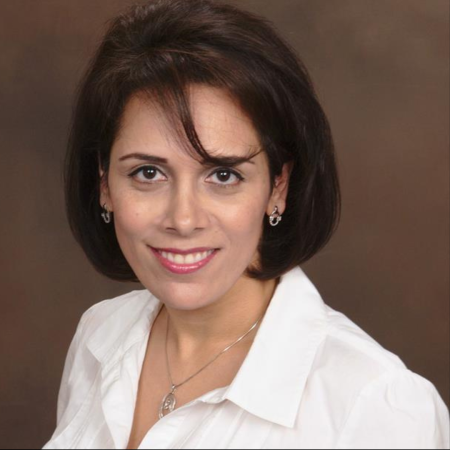 Shadnaz Asgari, a professor, smiles while wearing a white collared shirt and silver jewelry against a brown backdrop. Shadnaz Asgari, a professor, smiles while wearing a white collared shirt and silver jewelry against a brown backdrop.