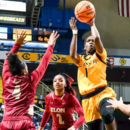 Beach basketball player Lovely Sonnier, wearing a yellow uniform, jumps for a shot while two Elon defenders in red attempt to block. Beach basketball player Lovely Sonnier, wearing a yellow uniform, jumps for a shot while two Elon defenders in red attempt to block.