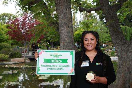 Student holding sign for first place in the Environmental science category