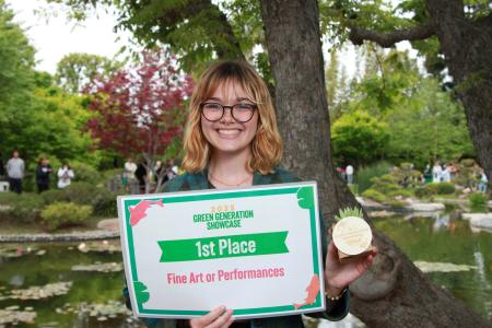 Student holding sign for first place in Fine arts category