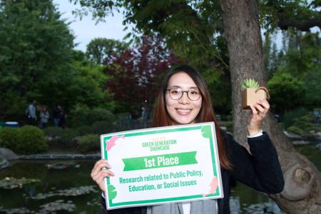 Student with sign for first place in Public policy, education, or social issues category