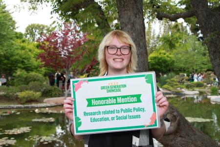Student holding honorable mention sign for public policy, education, or social issues