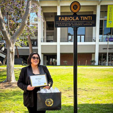 Employee of the Month Fabiola Tinti Employee of the Month Fabiola Tinti holds a certificate and gift bag near a sign with her name.