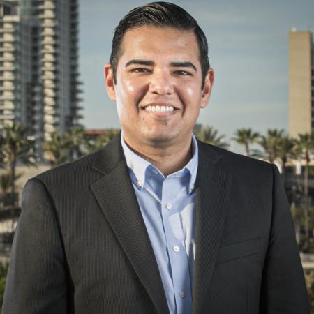 Robert Garcia Man in a suit jacket poses in front of cityscape