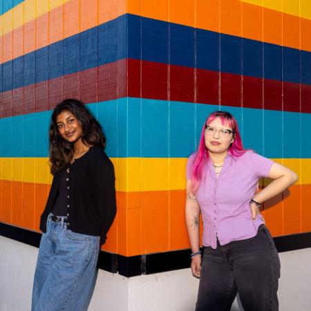 TV industry interns Two students stand in front of brightly colored wall