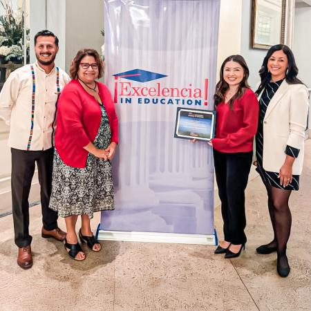CSULB group at Excelencia in Education event Four people stand beside an Excelencia in Education banner, with one person holding an award.