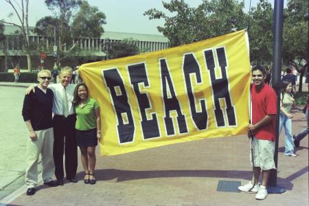People stand holding a yellow "BEACH" banner 