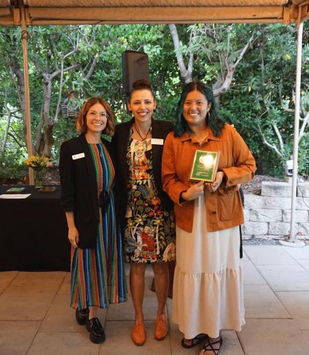 three people posing for a photo holding an award
