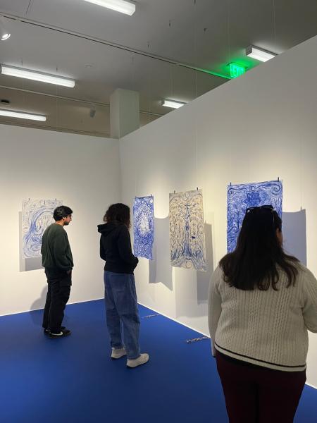 three people looking at blue art
