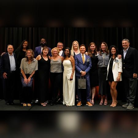 A group of former athletes poses together on a stage during a formal event.