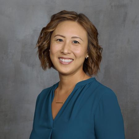 A person smiles in a studio-style professional headshot.