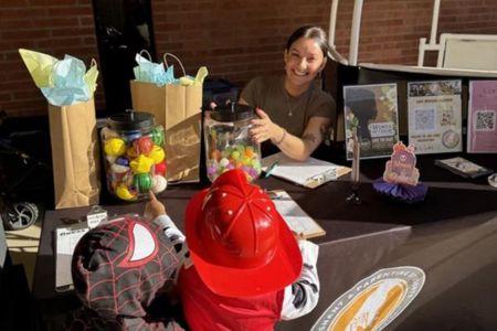 Peer mentor handing out candy to children at a Halloween event.